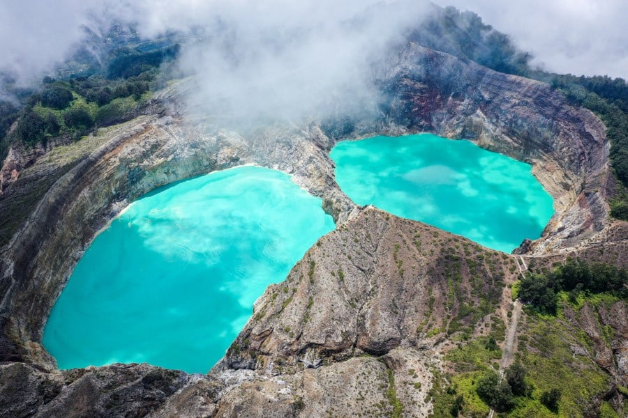 Drone shot of Kelimutu's crater lakes framed by the volcano cliff